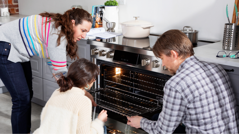 Three persons inspecting the inside of the range.