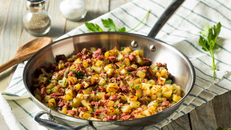 Corned beef hash cooked in a stainless steel skillet.