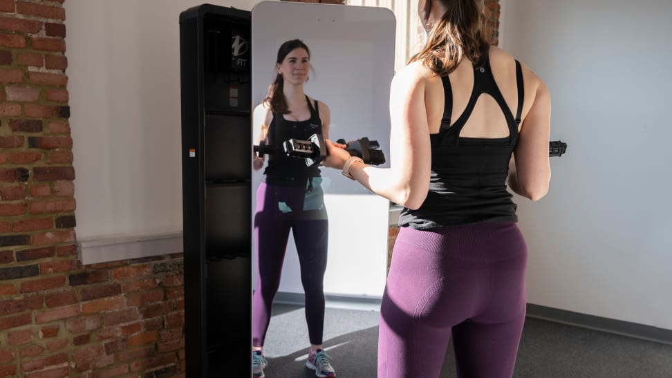 A woman doing bicep curls in front of the ProForm Vault workout mirror.