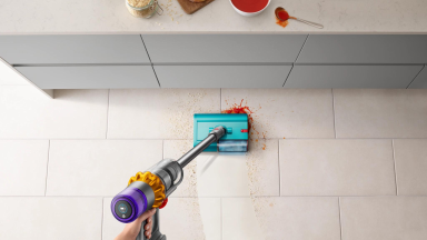 The Dyson Submarine wet roller head cleans up a messy stain on a white kitchen floor.