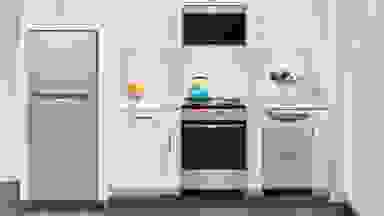 A small kitchen with a refrigerator, an oven range, utensils on the countertop, and so on.