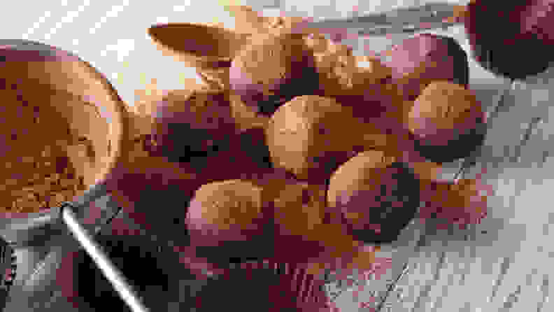 Chocolate truffles sprinkled with cocoa powder close-up on the table.