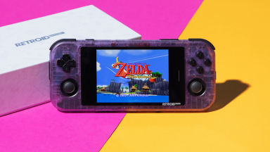 A clear purple gaming handheld with Android home screen on top of a grey Nintendo Switch