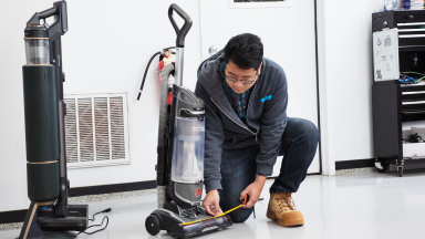 A man in a lab measuring the width of a vacuum.