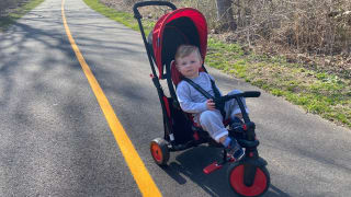 A toddler pauses from cycling on the SmarTrike Folding Stroller Trike.