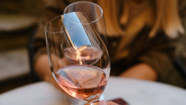 Person holding out wine glass to do a cheers gesture.