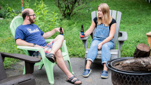 Man and woman sitting in adirondack chairs talking.