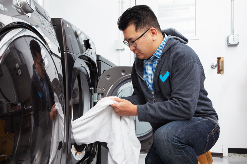 A person pulling a white piece of laundry out of a dryer.