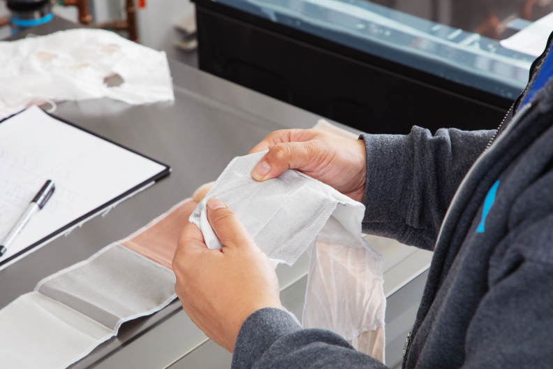 A person pulls a piece of white material in their hands