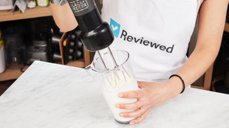 A person using the Black & Deck Kitchen Wand and mixing white liquid inside a container.