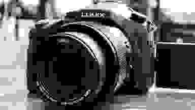 Monochrome close-up of a Lumix superzoom digital camera.