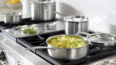 A Cuisinart cookware set is in use on a stovetop.