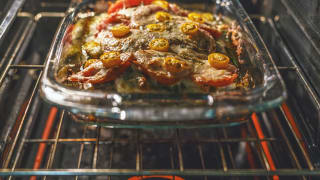 A rectangular Pyrex dish filled with food bakes in an oven.