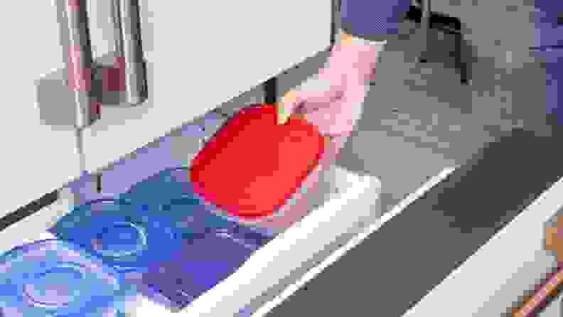 Lab technician placing ballast container inside of freezer drawer on refrigerator.