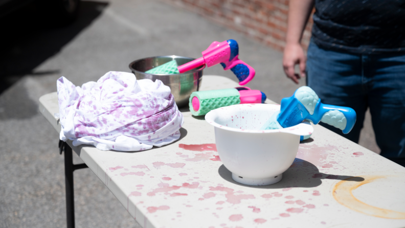 Water guns filled with wine and beer sit on bowls on a table.